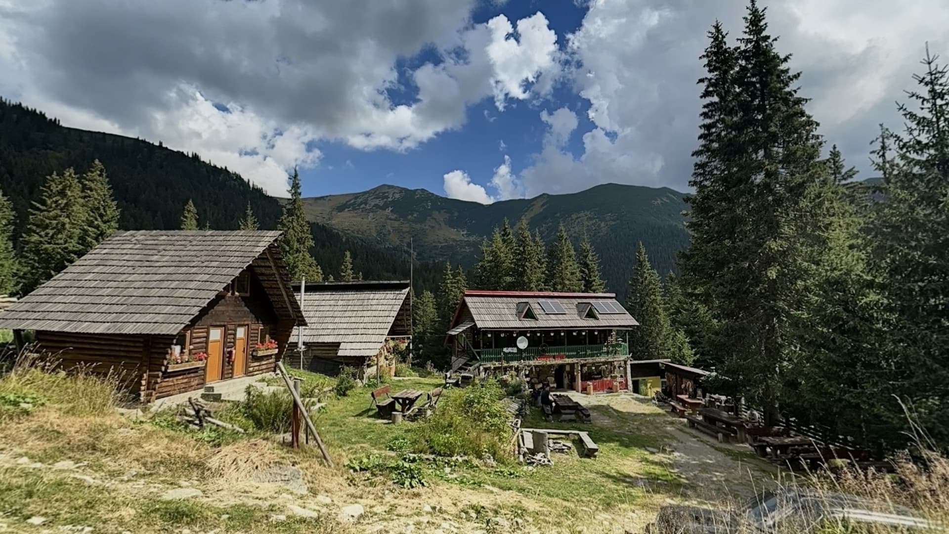 The wooden huts in the clearing, with the Retezat ridge behind